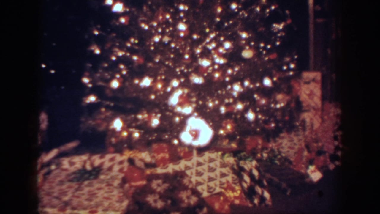 1962 Blainsport, Pennsylvania frame showing bright tree lights, ornaments, and wrapped gifts under the Christmas tree.
