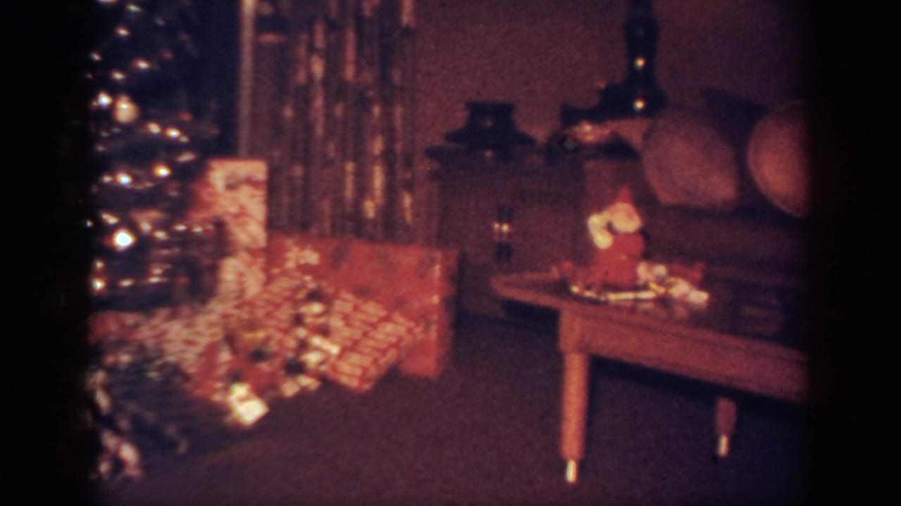 Wrapped Christmas presents near a tree, with a coffee table and sofa visible.