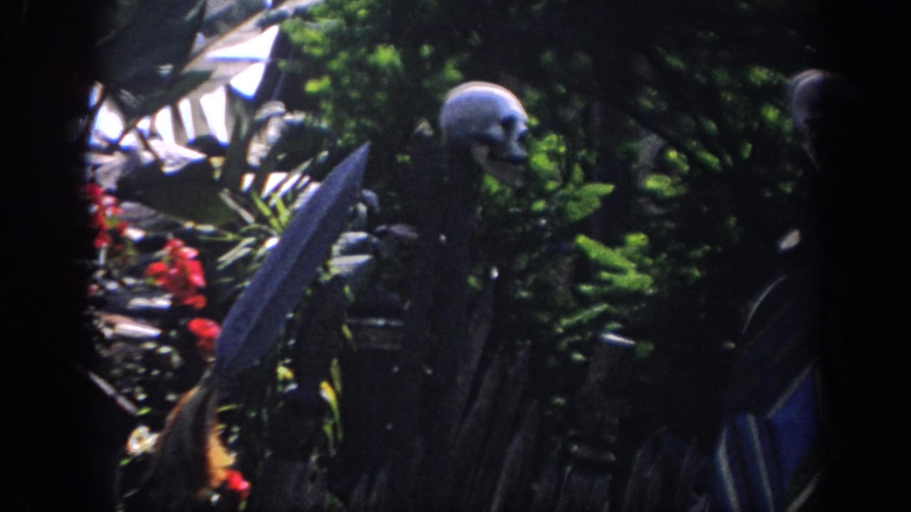 1962 Anaheim 8mm frame showing skull props on stakes beside a spear-like point in dense attraction foliage.