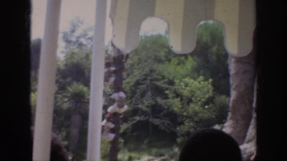 End frame of the 1962 Anaheim ride view, with scalloped canopy trim, window posts, greenery, and a partial animal figure near the bus.