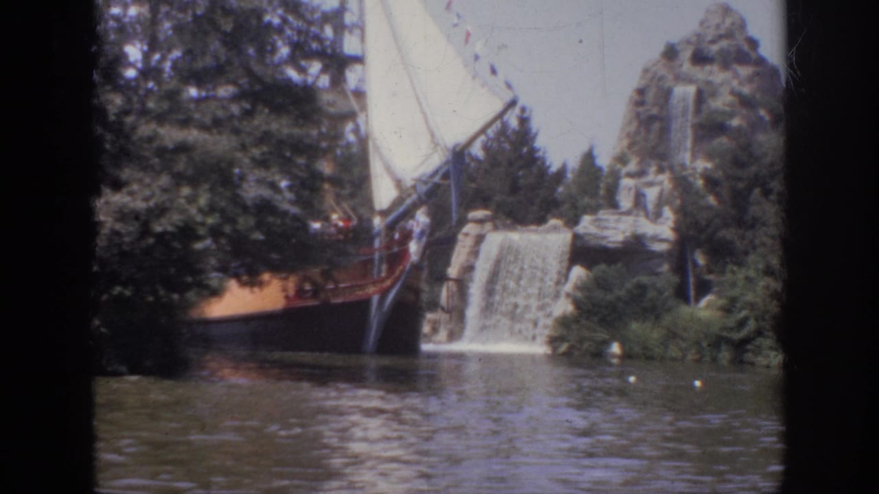 1962 Anaheim 8mm frame showing a themed wooden boat with white sails near an artificial waterfall and lagoon.