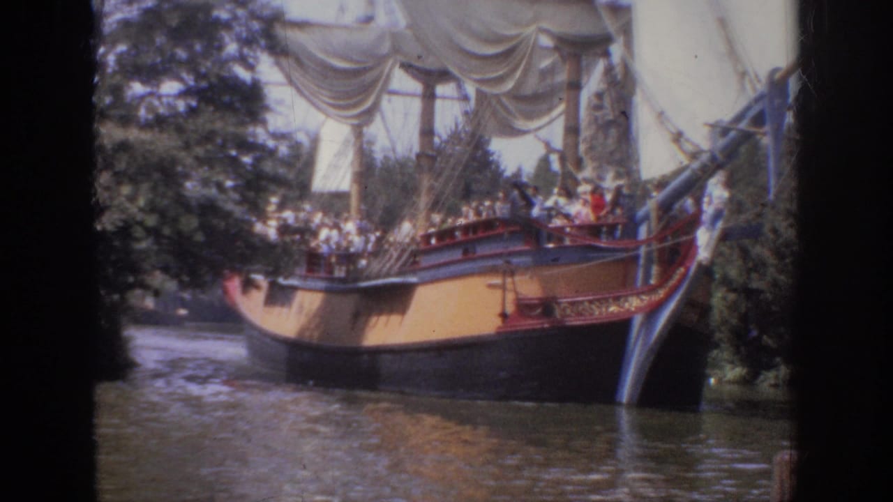 1962 Anaheim Disneyland home-movie frame showing a themed sailing ship with visitors on deck moving along a tree-lined waterway.