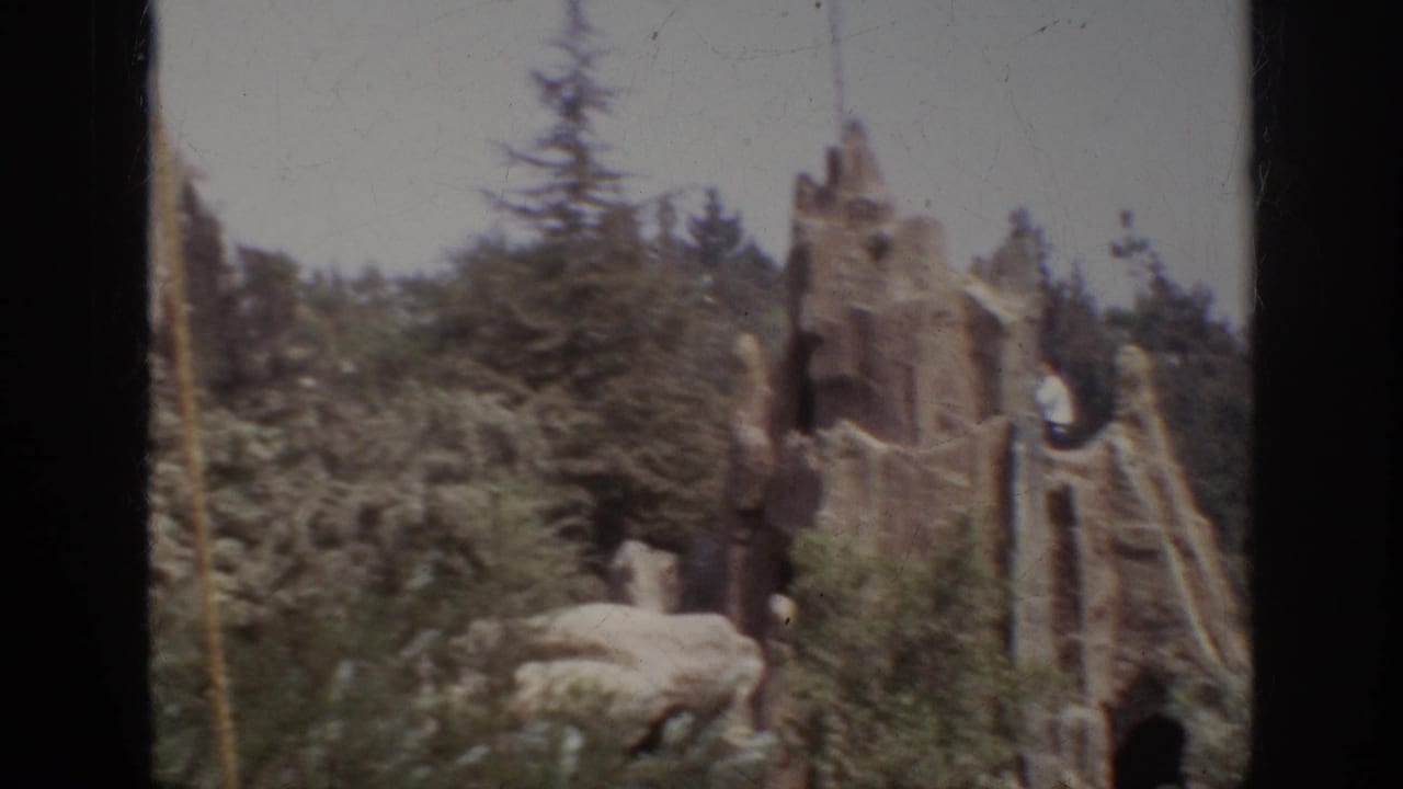Worker on a stone-like tower with trees and rockwork below.