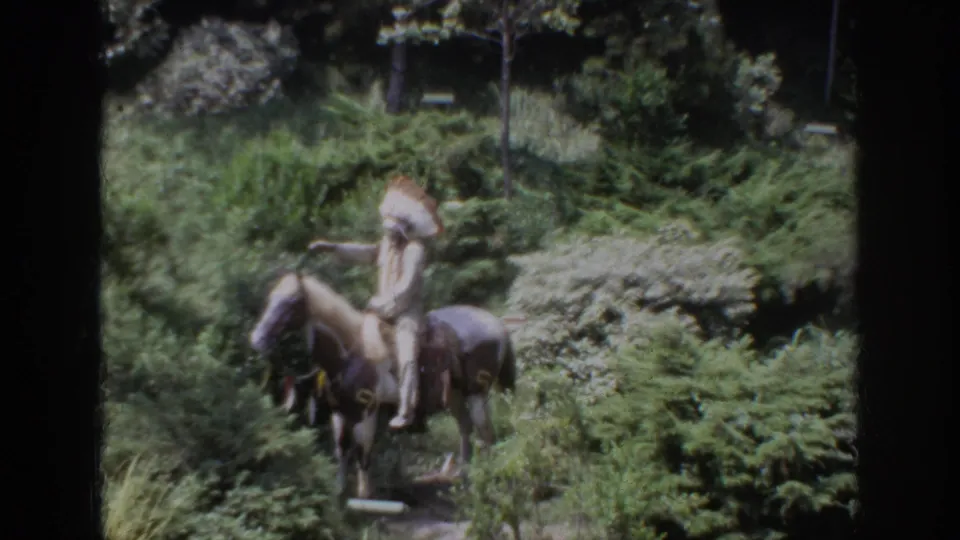 1962 Anaheim frame of a Native American horseback figure in a wooded attraction setting with visible 8mm film texture.