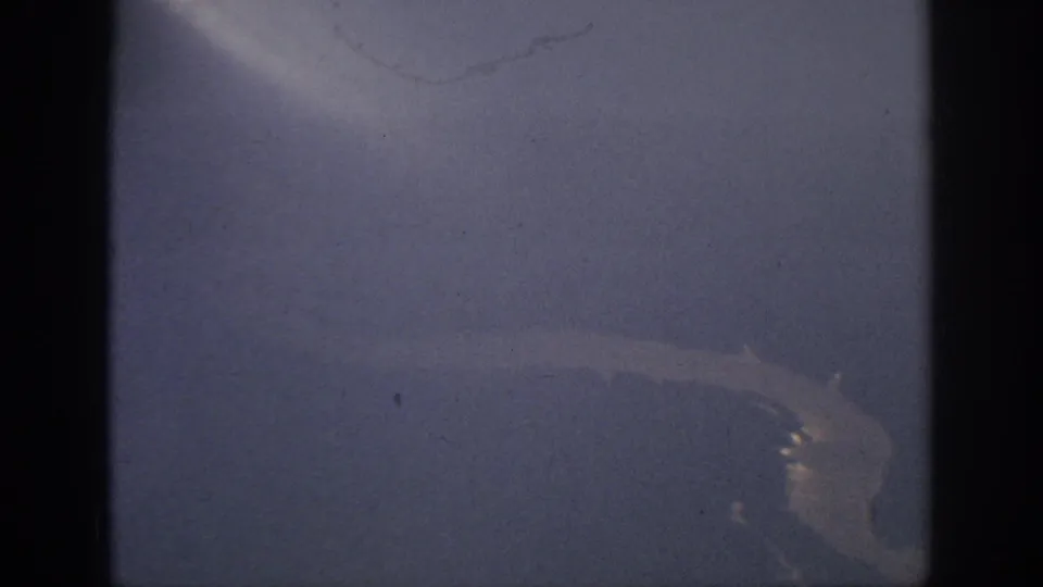 A hazy 8mm aerial view from the Anaheim, California clip, with a pale curved river line near the lower right.