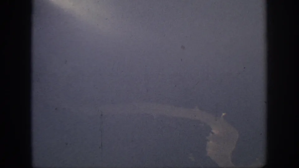 Final 1962 Anaheim-area aerial frame showing a pale river bend below a blue-purple haze, bordered by the 8mm film gate.
