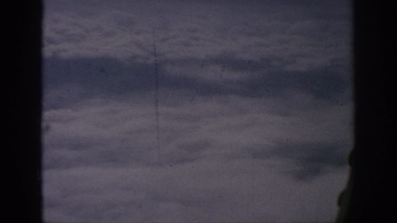 Cloud layer seen through an airplane window with dark vertical framing.