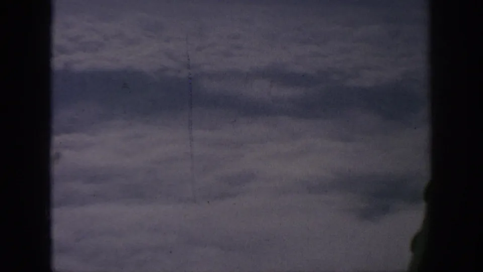 A 1962 passenger-window view above a broad cloud layer, bordered by dark airplane-window structure.