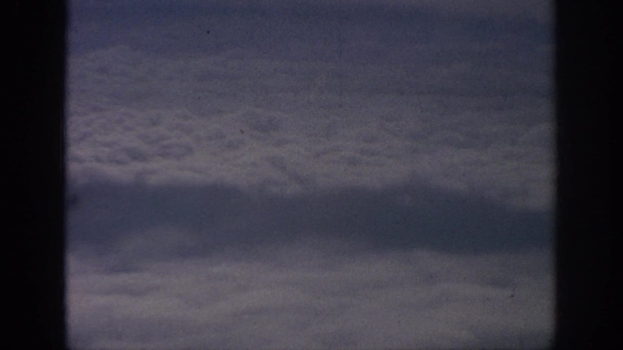 Clouds and sky divided by dark airplane window framing.