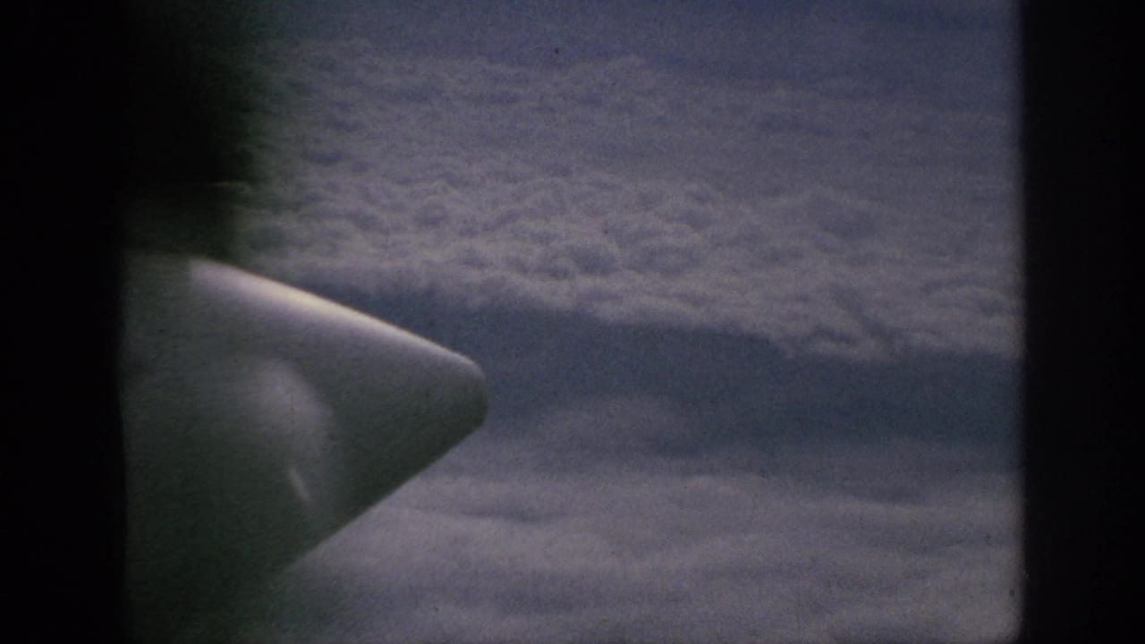 Cloud tops seen from an aircraft window, with a pale wingtip or housing near the left side.