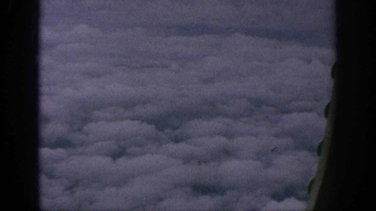 Cloud tops seen through dark airplane window framing.