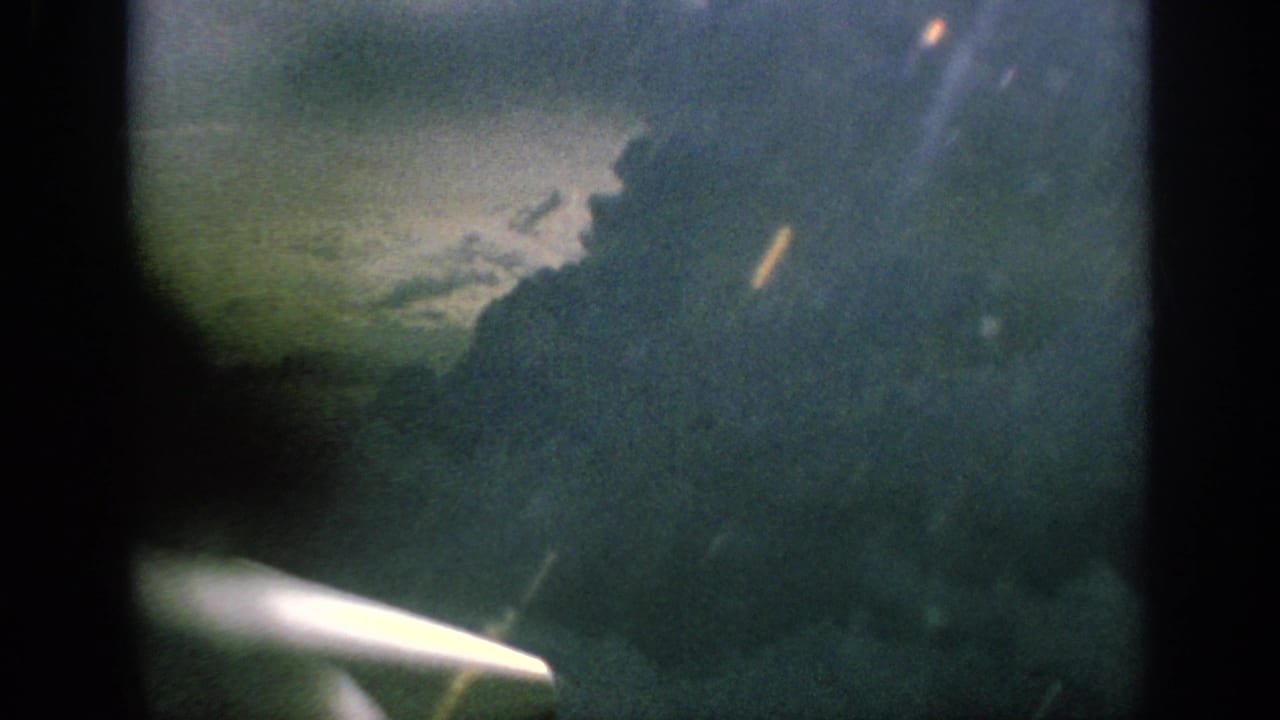 1962 Anaheim airplane-window view with a bright propeller blur below clouded sky and soft film exposure.
