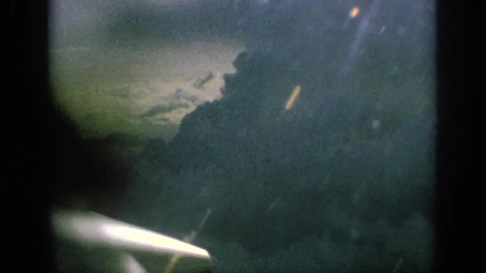 1962 Anaheim airplane-window view with a bright propeller blur below clouded sky and soft film exposure.