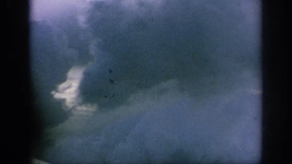 1962 8mm airplane-window view with soft blue cloud forms, dark frame edges, and no visible people or markings.