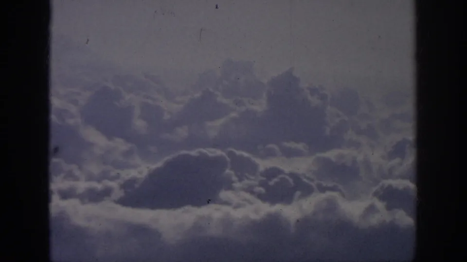 The final 1962 8mm frame keeps a steady aerial view of cloud banks through dark borders, with visible grain and dust marks.