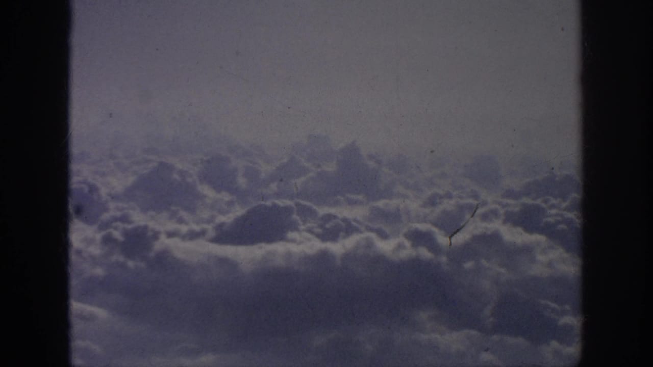 Wide cloudscape with dark vertical borders and visible dust on the film scan.