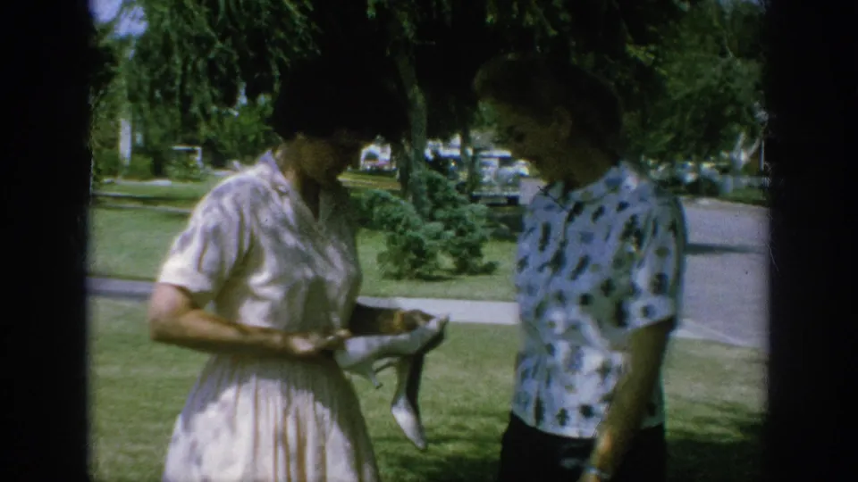 In Anaheim, California, 1962, two women stand in partial shade on a residential lawn while looking down at the shoes.
