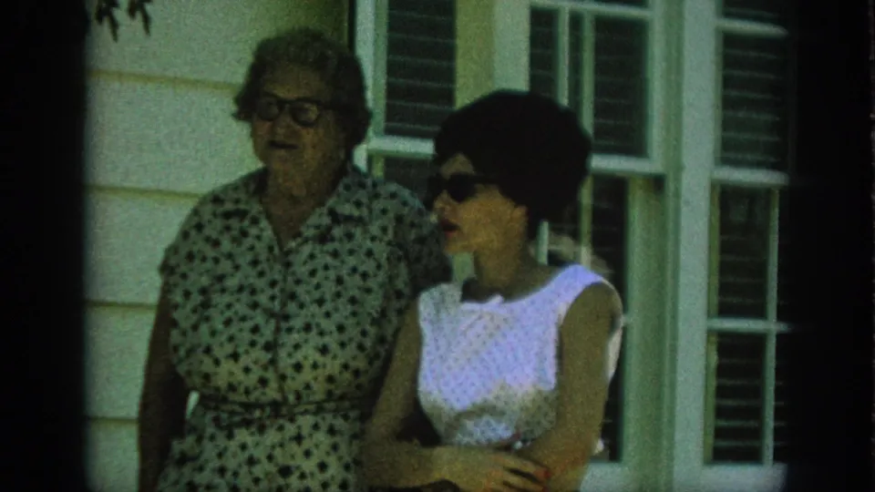 A closer 1962 Anaheim frame shows the older woman in glasses beside the younger woman in sunglasses during their porch conversation.