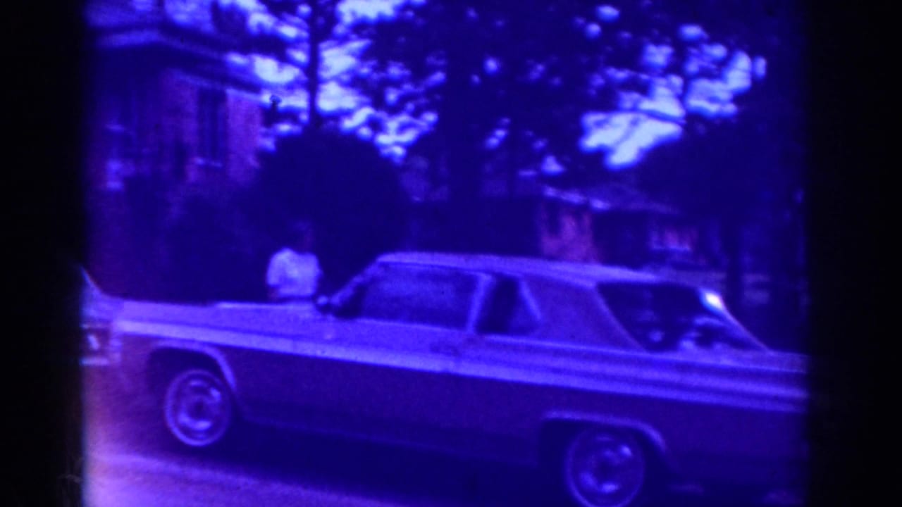 Raleigh 1962 home-movie frame with a classic sedan on a residential street under a strong blue-purple cast.