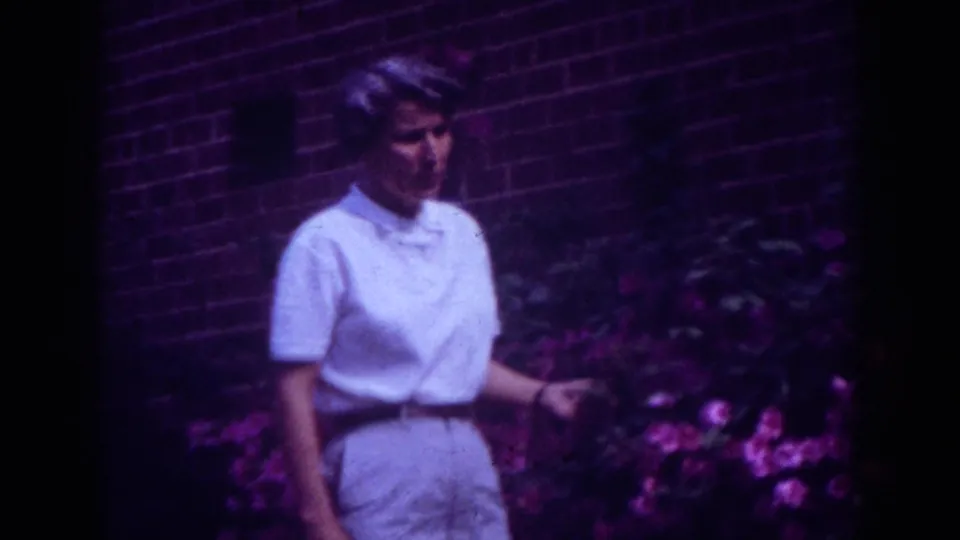 Closer 1962 Raleigh frame showing the woman's face and upper body near a pink flowering shrub.