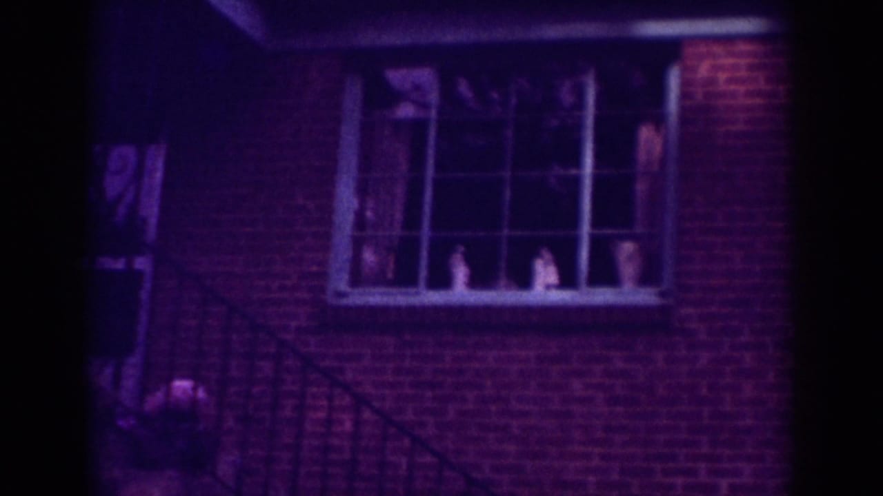 Brick wall with large window and porch railing in low light.