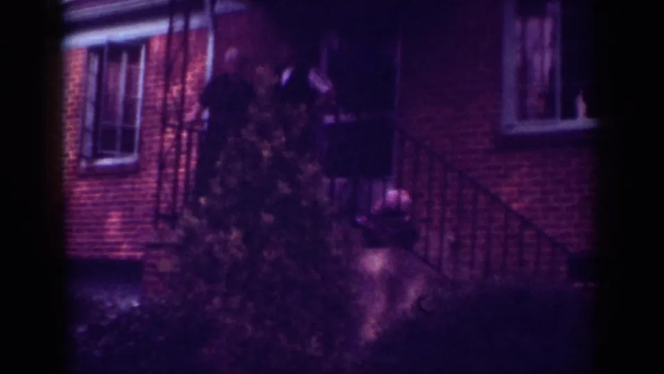 1962 Raleigh frame showing a person standing on or near a porch by metal railings, brickwork, and a front shrub.