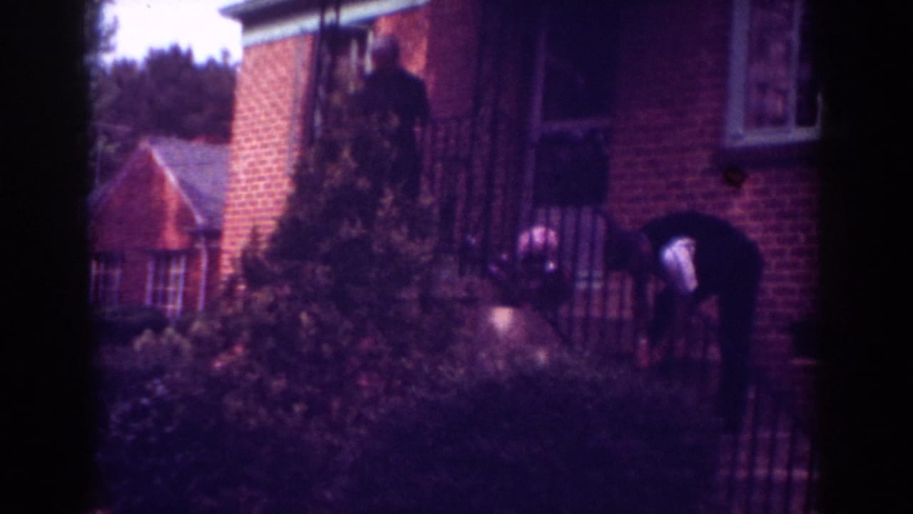 Two adults near the porch and steps of a brick house.