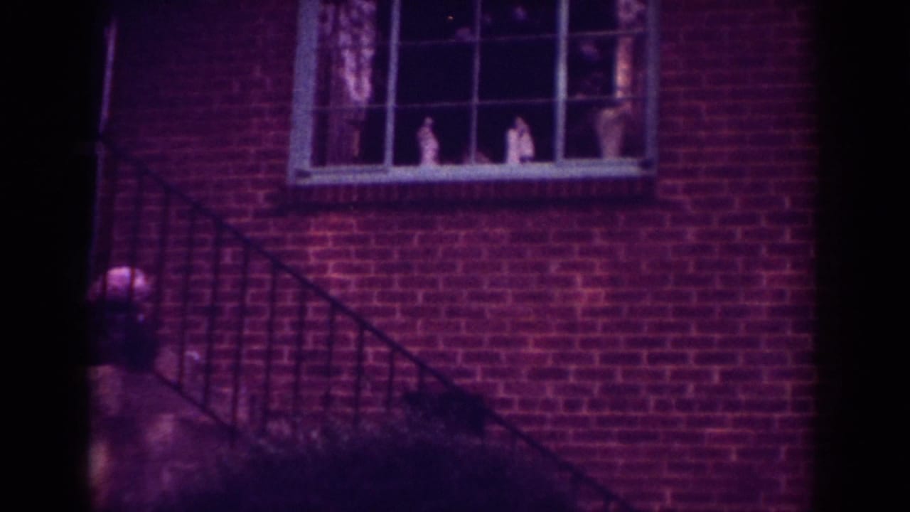 A Raleigh brick house exterior shows the stair rail and a divided window with faint figures or objects visible behind the glass.
