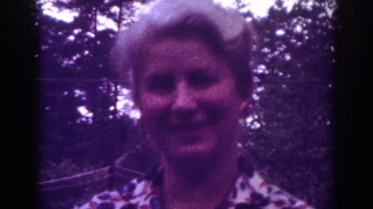 Blonde woman faces the camera outdoors, smiling softly.
