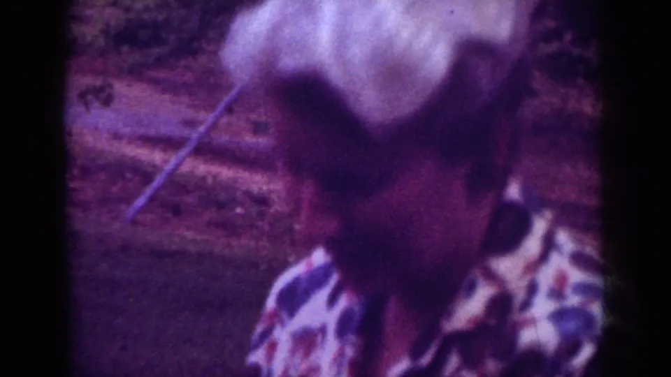 Soft 8mm frame from Raleigh, 1962, showing the older woman close to camera with her white hair and patterned blouse visible.