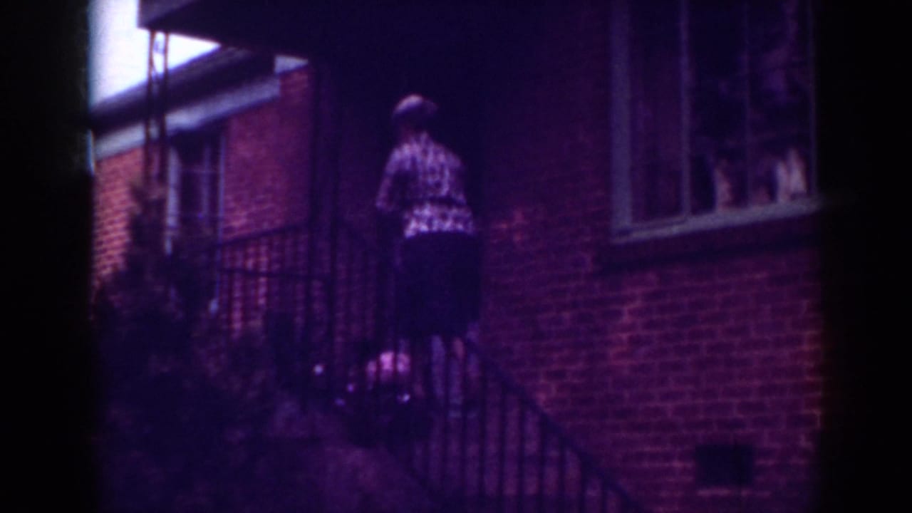 In 1962 Raleigh home-movie footage, an elderly woman climbs brick exterior steps beside a dark railing.