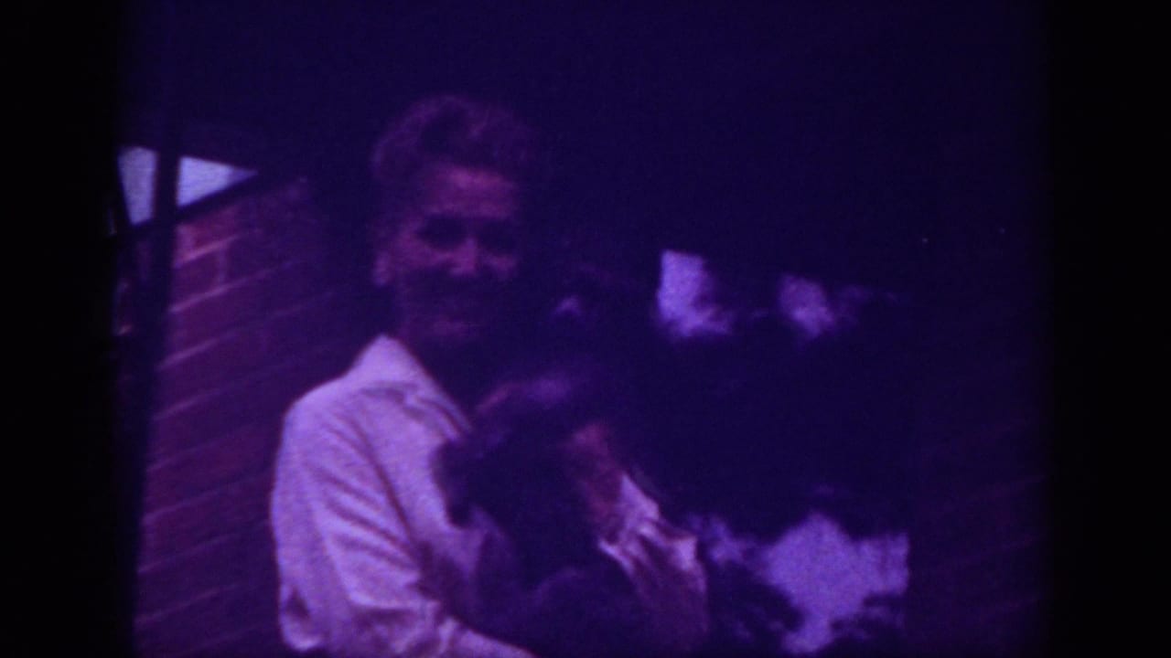 Woman smiles while holding a dark-furred pet close to her chest.