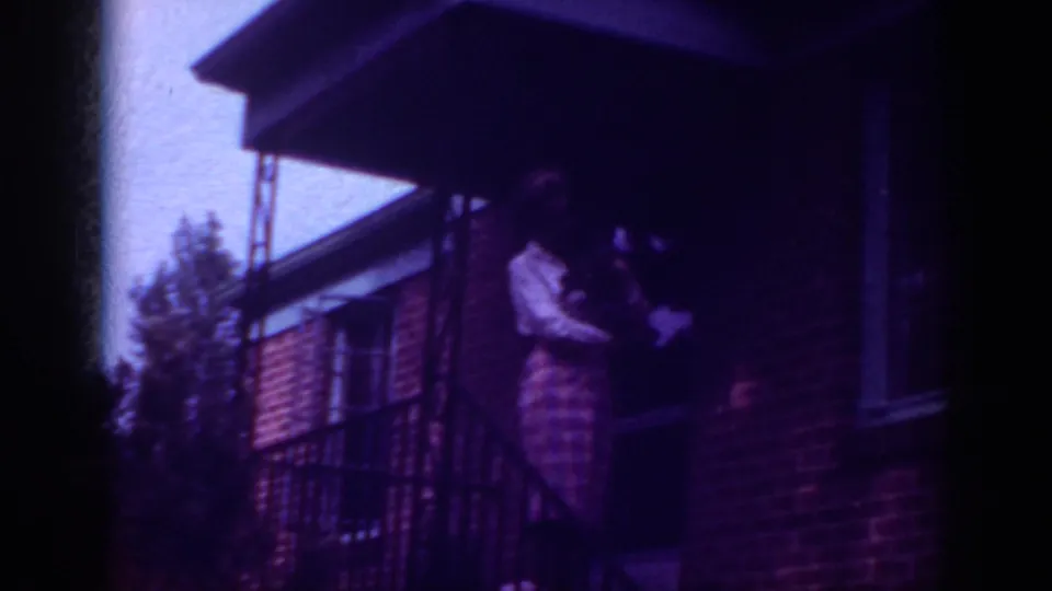 Final 1962 Raleigh frame with a woman and small dog on a shaded brick porch under a dark overhang.