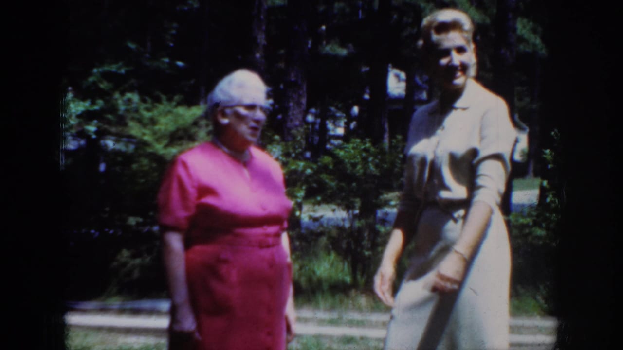 In Raleigh, North Carolina, 1962 home-movie footage, two adult women stand in a sunlit yard among trees and shrubs.