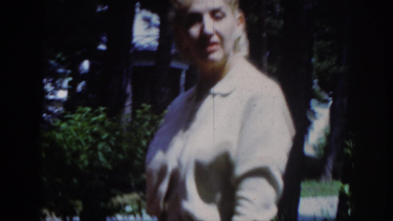Younger woman in a light blouse stands outdoors beside trees.
