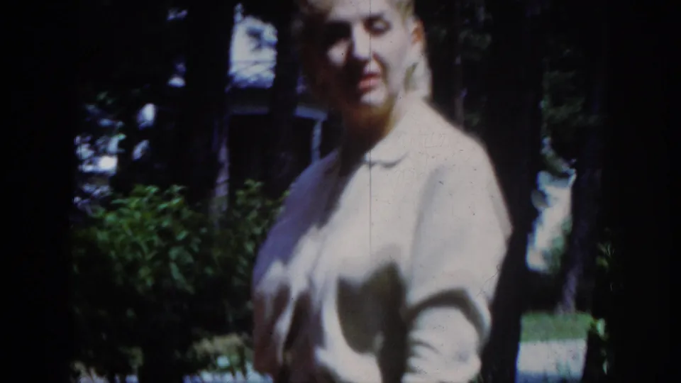 Younger woman in a pale blouse appears near trees in the Raleigh 1962 outdoor home-movie scene.