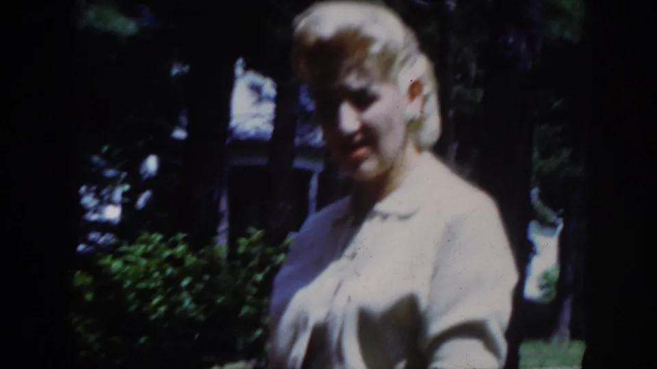 The younger woman in a pale top is seen closer to camera in the wooded Raleigh home-movie setting.