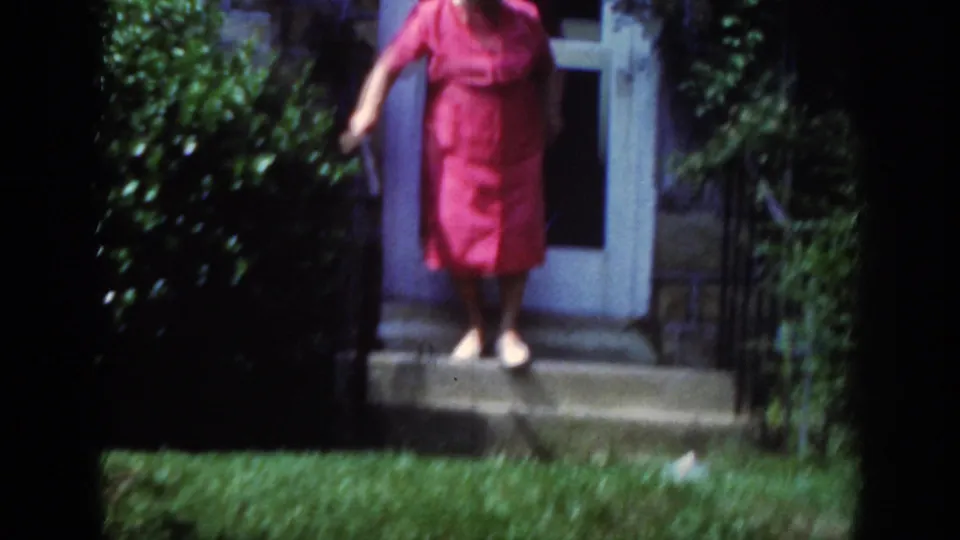 The 1962 home-movie frame shows the woman partway down the stone steps, partly soft from motion and film focus.
