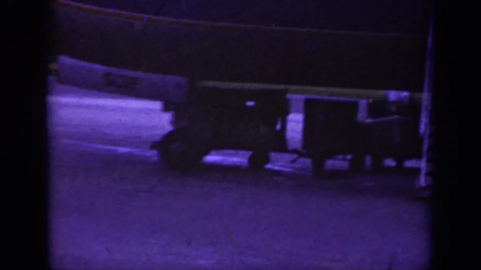 Luggage carts appear beneath the fuselage of a commercial airliner during nighttime airport handling in Raleigh, 1962.