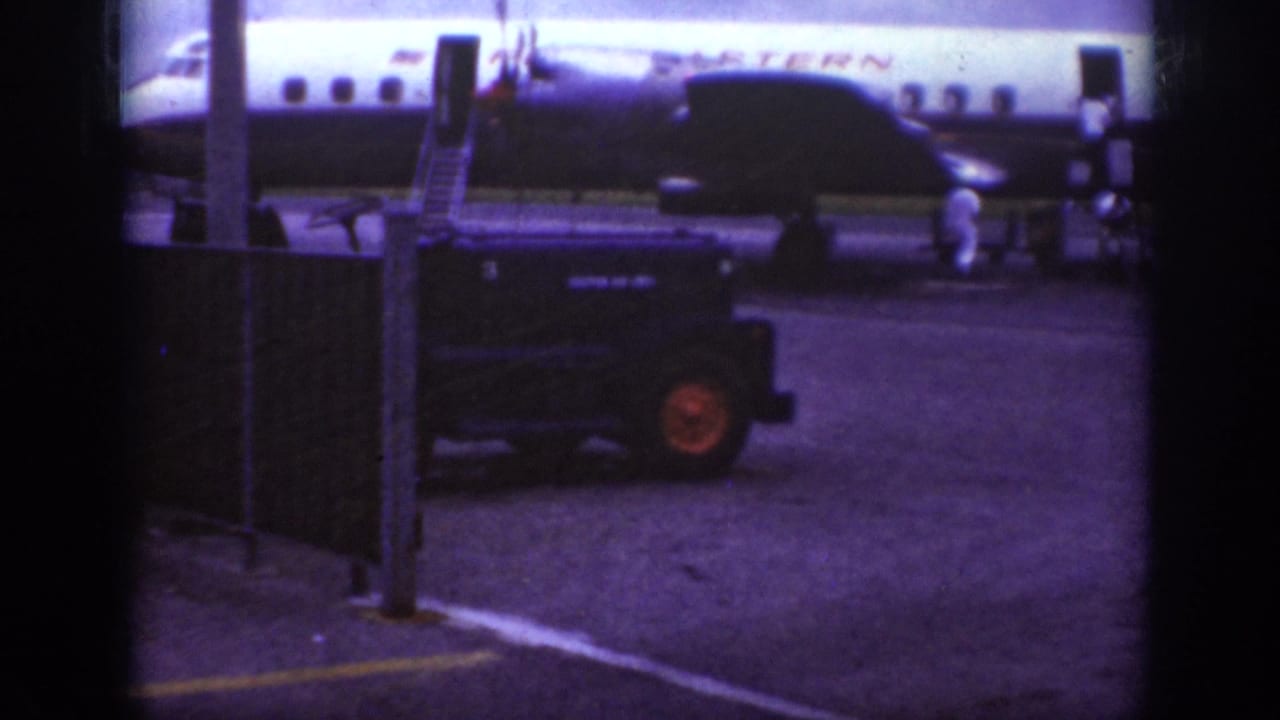 1962 Raleigh airport ramp view with a Western Airlines aircraft, mobile boarding stairs, fencing, and a dark ground vehicle.