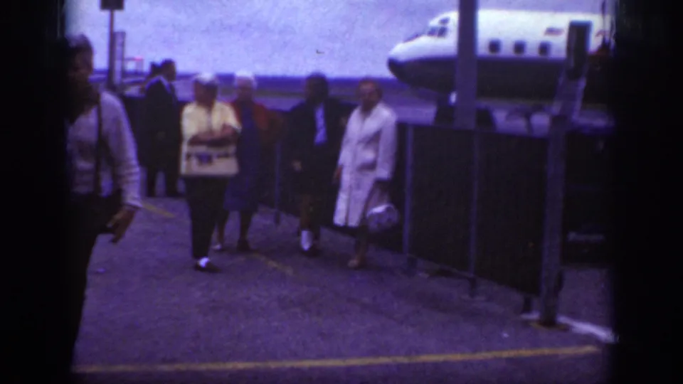 A small group of travelers walks toward the camera on the Raleigh airport ramp, with the Western Airlines plane and mobile stairs in the background.