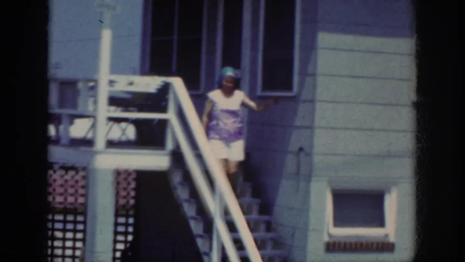 The Raleigh 1962 footage shows a woman partway down outdoor stairs, framed by house siding, windows, and a railing.