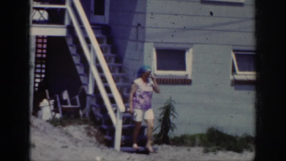 At the end of the Raleigh home-movie shot, the woman reaches the ground near the exterior stairs and small tree.