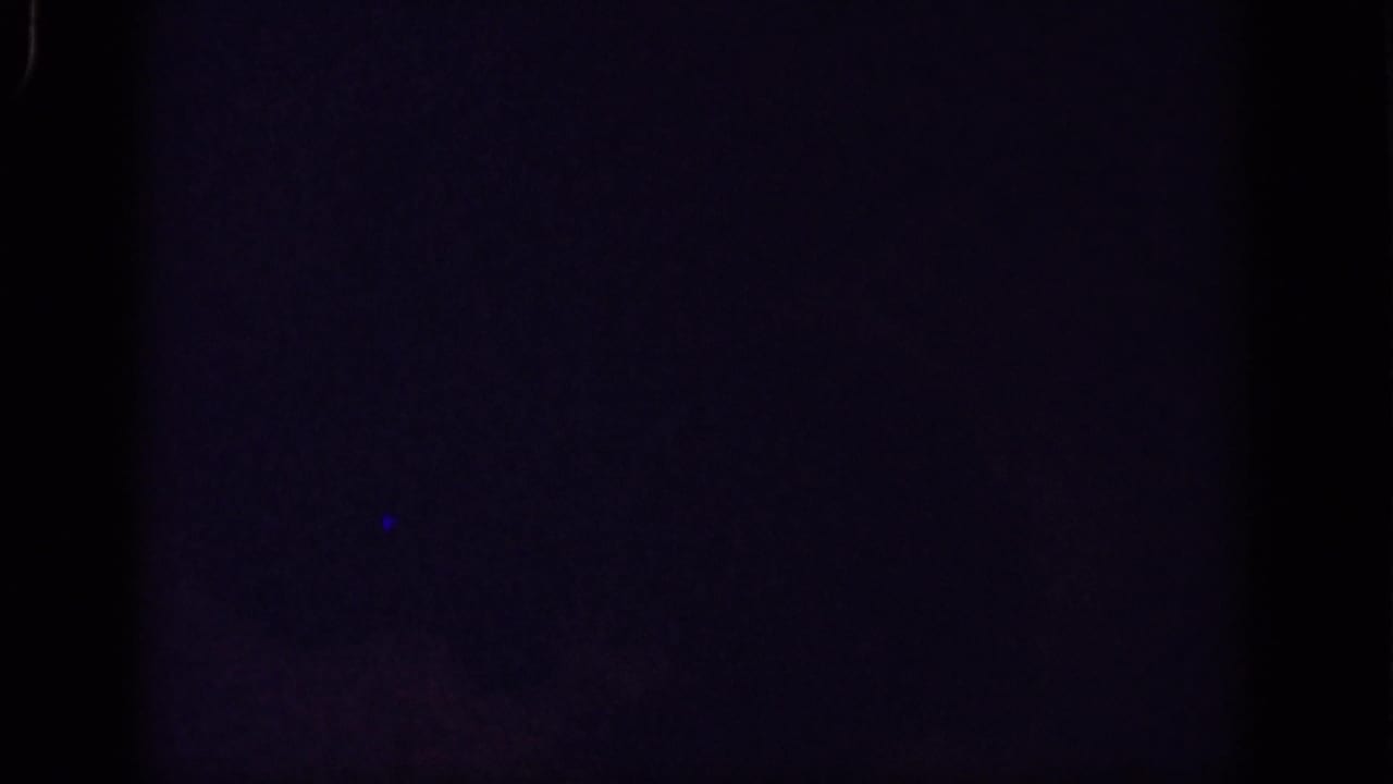 Dark underexposed 8mm frame from the 1962 Yorba Linda clip, with faint blue tone and visible film gate edges.