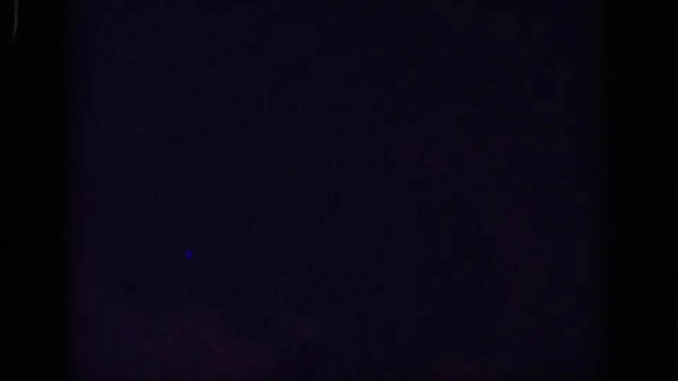 Dark underexposed 8mm frame from the 1962 Yorba Linda clip, with faint blue tone and visible film gate edges.