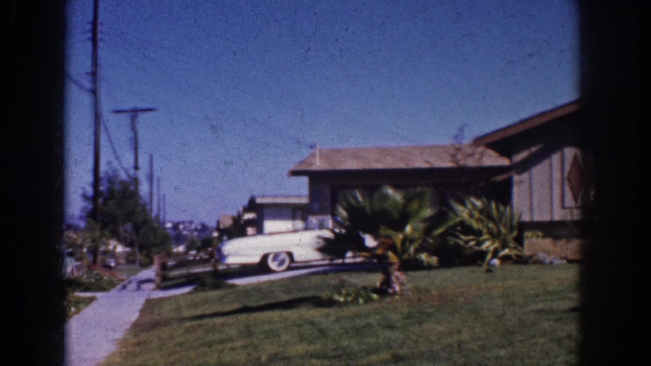Sidewalk, utility poles, parked car, and ranch-style house on a sunny block.