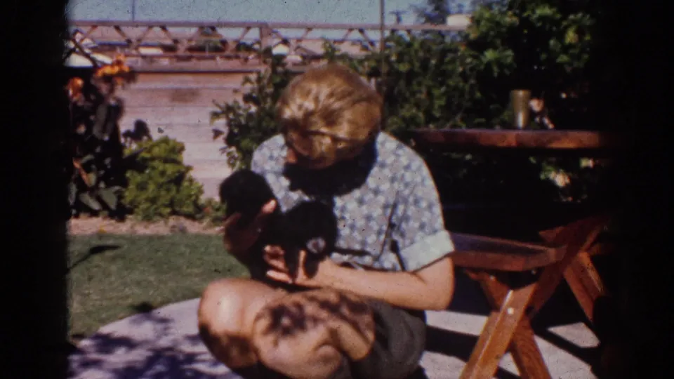 The final frame shows the young person looking down at the black puppy in the Yorba Linda backyard, framed by 8mm film edges.