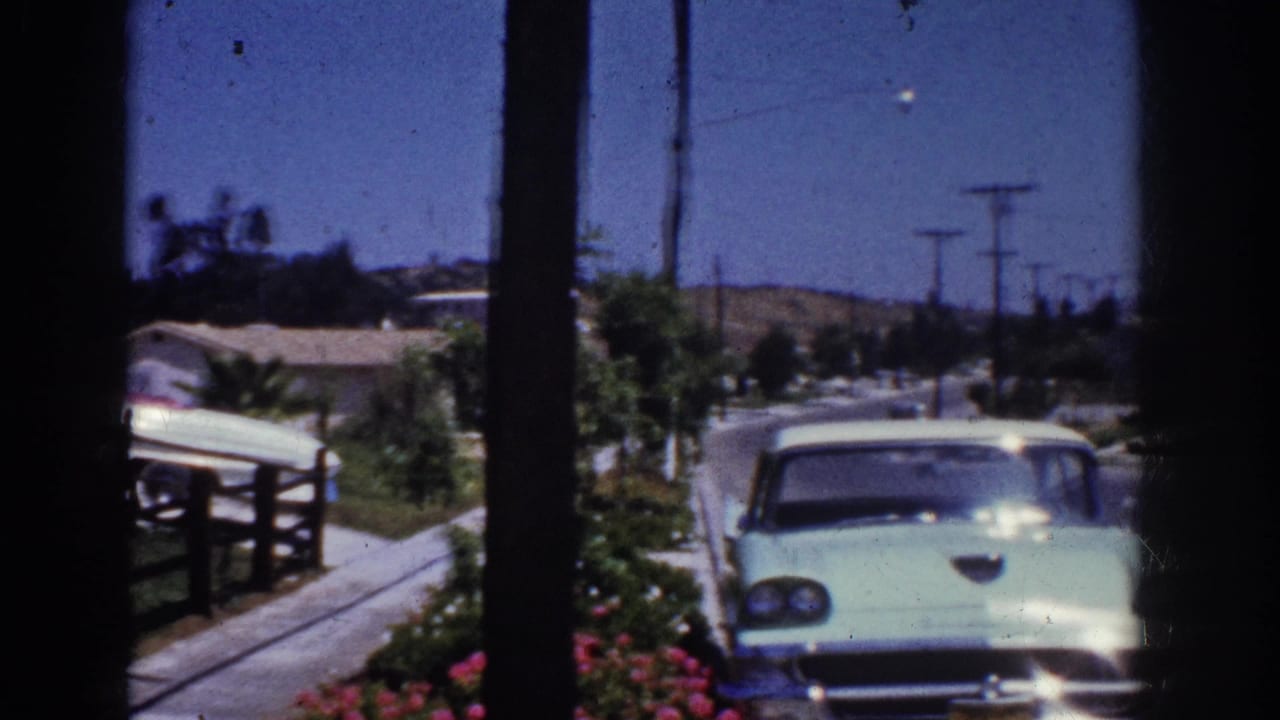 Yorba Linda residential street in 1962 with a light blue sedan, low fences, landscaping, utility poles, and single-story homes.