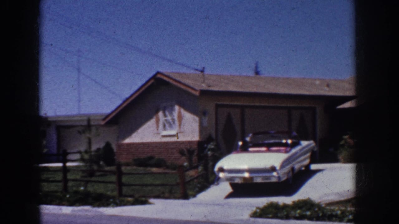 1962 Yorba Linda home-movie frame showing a white convertible in the driveway of a stucco house with brick base and garage.