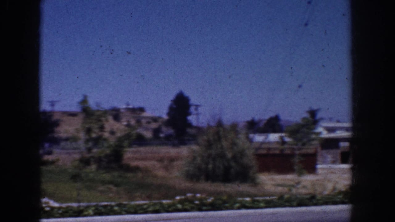 Yorba Linda suburban landscape with dry ground, low houses, utility lines, trees, and a dark window divider in the foreground.